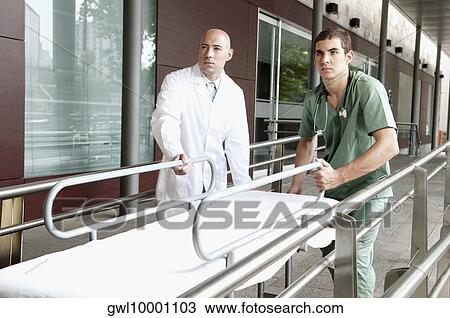 Doctor and a male nurse pushing a hospital gurney View Large Photo Image Stock Image - Doctor and a male nurse pushing a hospital gurney. Fotosearch