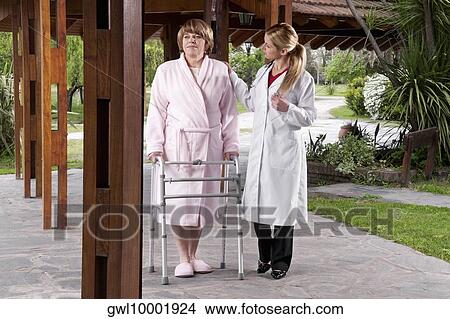 Doctor assisting a patient in walking in a rehabilitation centre View Large Photo Image Picture - Doctor assisting a patient in walking in a rehabilitation centre. Fotosearch