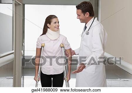 Doctor assisting a patient to walk in a hospital corridor View Large Photo Image Stock Photo - Doctor assisting a patient to walk in a hospital corridor. Fotosearch