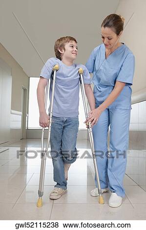 Doctor assisting a patient to walk View Large Photo Image Stock Photo - Doctor assisting a patient to walk. Fotosearch