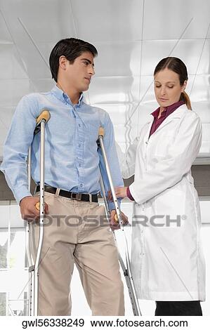 Doctor assisting a patient to walk View Large Photo Image Stock Photo - Doctor assisting a patient to walk. Fotosearch