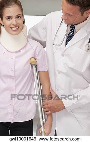 Stock Photograph - Doctor assisting a patient to walk. Fotosearch