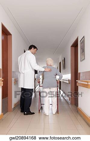 Doctor assisting a woman in walking View Large Photo Image Stock Photo - Doctor assisting a woman in walking. Fotosearch