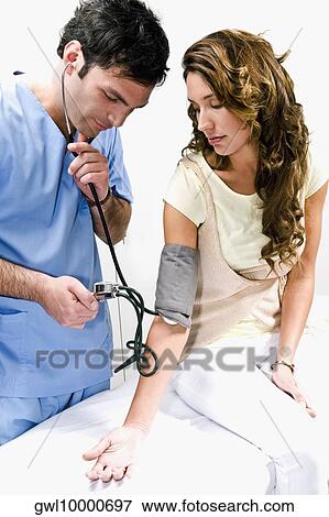 Doctor checking a woman's blood pressure View Large Photo Image Stock Photo - Doctor checking a woman's blood pressure. Fotosearch