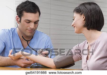Doctor checking a woman's blood pressure View Large Photo Image Stock Photograph - Doctor checking a woman's blood pressure. Fotosearch