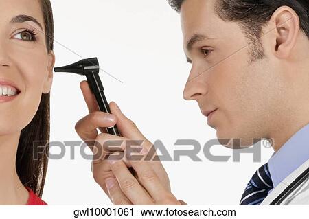 Doctor checking a woman's ear with an otoscope View Large Photo Image Stock Image - Doctor checking a woman's ear with an otoscope. Fotosearch