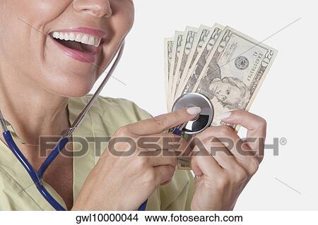 Doctor checking currency notes with a stethoscope View Large Photo Image Picture - Doctor checking currency notes with a stethoscope. Fotosearch