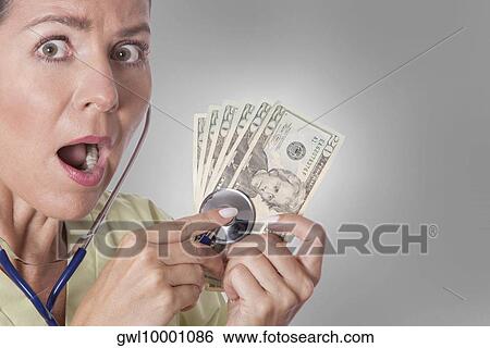 Doctor checking currency notes with a stethoscope View Large Photo Image Stock Photograph - Doctor checking currency notes with a stethoscope. Fotosearch
