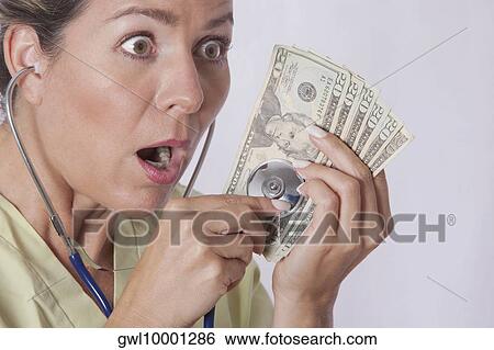 Doctor checking currency notes with a stethoscope View Large Photo Image Stock Photograph - Doctor checking currency notes with a stethoscope. Fotosearch