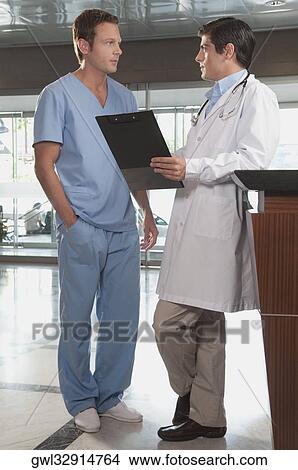 Doctor discussing with a male nurse discussing View Large Photo Image Picture - Doctor discussing with a male nurse discussing. Fotosearch