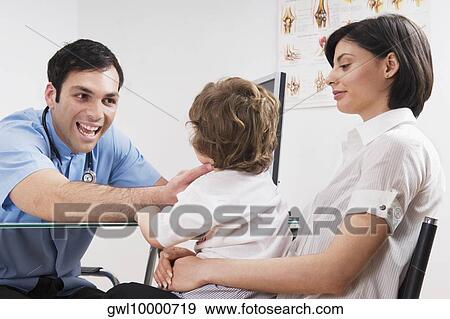 Doctor examining a baby boy sitting on his mother's lap View Large Photo Image Stock Photo - Doctor examining a baby boy sitting on his mother's lap. Fotosearch