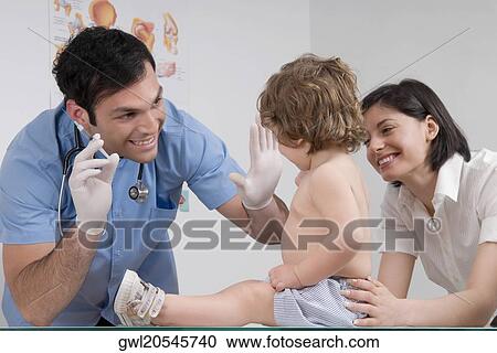 Doctor examining a baby boy sitting with his mother View Large Photo Image Stock Image - Doctor examining a baby boy sitting with his mother. Fotosearch