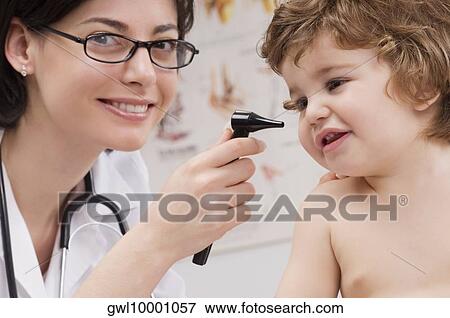Stock Photo - Doctor examining a baby boy with an otoscope. Fotosearch