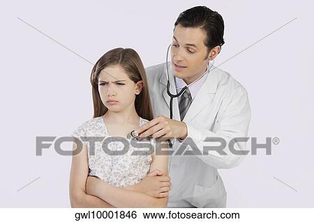 Doctor examining a girl with a stethoscope View Large Photo Image Stock Photograph - Doctor examining a girl with a stethoscope. Fotosearch