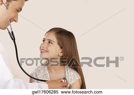 Doctor examining a girl with a stethoscope View Large Photo Image Stock Photography - Doctor examining a girl with a stethoscope. Fotosearch