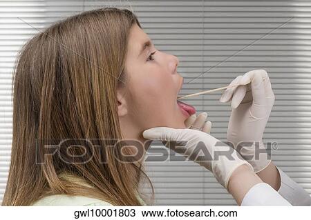 Doctor examining a girl's mouth with a tongue depressor View Large Photo Image Stock Image - Doctor examining a girl's mouth with a tongue depressor. Fotosearch