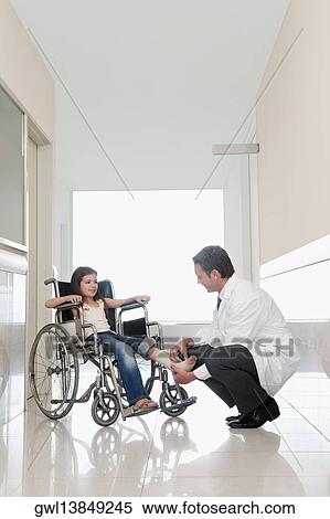 Doctor examining a patient's leg in a hospital corridor View Large Photo Image Stock Photography - Doctor examining a patient's leg in a hospital corridor. Fotosearch