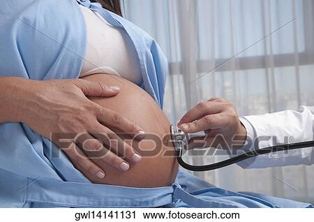 Doctor examining a pregnant woman with a stethoscope View Large Photo Image Stock Image - Doctor examining a pregnant woman with a stethoscope. Fotosearch