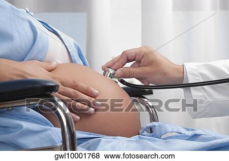 Doctor examining a pregnant woman with a stethoscope View Large Photo Image Stock Photo - Doctor examining a pregnant woman with a stethoscope. Fotosearch