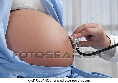 Doctor examining a pregnant woman with a stethoscope View Large Photo Image Stock Photography - Doctor examining a pregnant woman with a stethoscope. Fotosearch