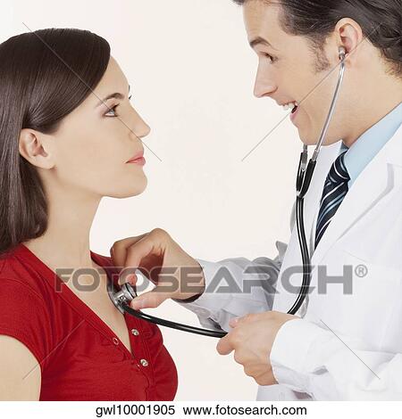 Doctor examining a woman with a stethoscope View Large Photo Image Stock Photography - Doctor examining a woman with a stethoscope. Fotosearch