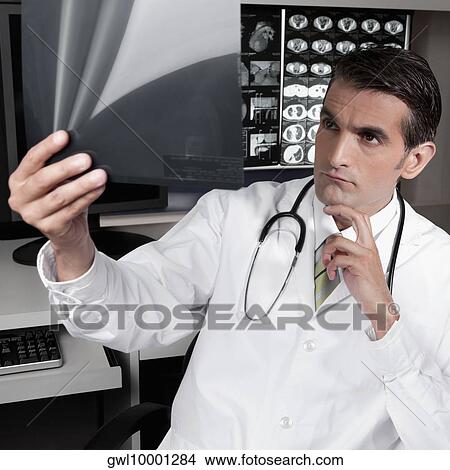 Picture - Doctor examining an x-ray report. Fotosearch
