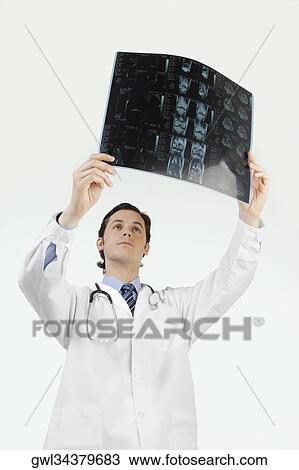 Stock Image - Doctor examining an x-ray report. Fotosearch