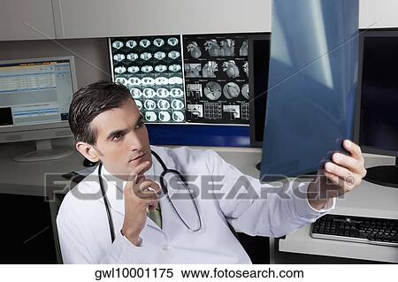 Doctor examining an x-ray report View Large Photo Image Stock Photography - Doctor examining an x-ray report. Fotosearch