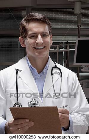 Doctor holding a clipboard and smiling View Large Photo Image Stock Image - Doctor holding a clipboard and smiling. Fotosearch