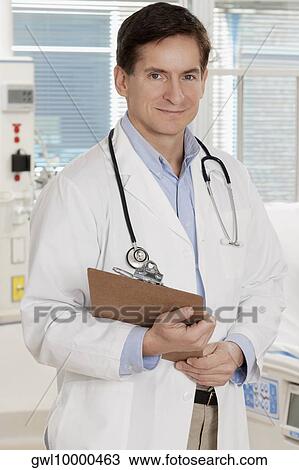 Doctor holding a clipboard and smiling View Large Photo Image Stock Image - Doctor holding a clipboard and smiling. Fotosearch