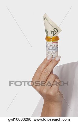 Doctor holding a pill bottle with a twenty currency note in it View Large Photo Image Stock Image - Doctor holding a pill bottle with a twenty currency note in it. Fotosearch