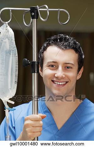 Doctor holding a saline drip stand and smiling View Large Photo Image Stock Image - Doctor holding a saline drip stand and smiling. Fotosearch