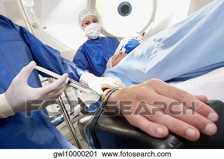 Doctor injecting patient's arm in an operating room View Large Photo Image Stock Image - Doctor injecting patient's arm in an operating room. Fotosearch