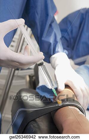 Doctor injecting patient's arm in an operating room View Large Photo Image Stock Image - Doctor injecting patient's arm in an operating room. Fotosearch
