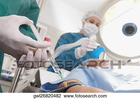 Doctor injecting patient's arm in an operating room View Large Photo Image Stock Image - Doctor injecting patient's arm in an operating room. Fotosearch