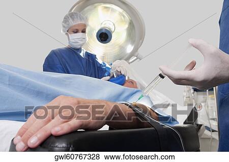 Doctor injecting patient's arm in an operating room View Large Photo Image Stock Photo - Doctor injecting patient's arm in an operating room. Fotosearch
