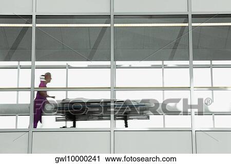 Doctor pushing a patient on a gurney View Large Photo Image Stock Image - Doctor pushing a patient on a gurney. Fotosearch