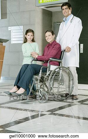 Doctor pushing a woman in a wheelchair View Large Photo Image Stock Image - Doctor pushing a woman in a wheelchair. Fotosearch