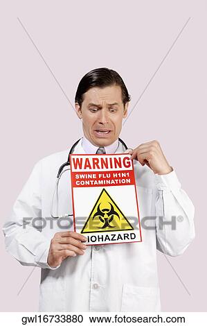 Stock Image - Doctor showing a Biohazard warning sign and crying. Fotosearch