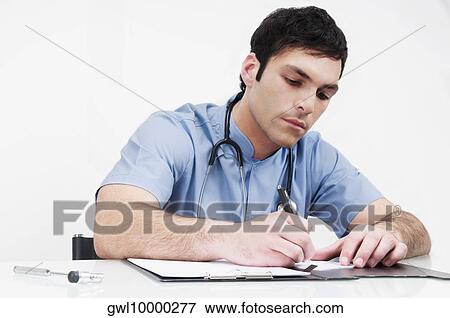 Doctor sitting at a table and writing in a file View Large Photo Image Stock Photo - Doctor sitting at a table and writing in a file. Fotosearch