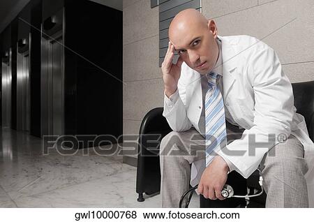 Doctor sitting on a chair and looking stressed View Large Photo Image Stock Photo - Doctor sitting on a chair and looking stressed. Fotosearch