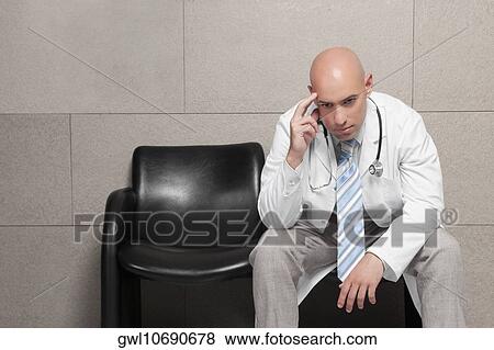 Stock Photo - Doctor sitting on a chair and looking stressed. Fotosearch