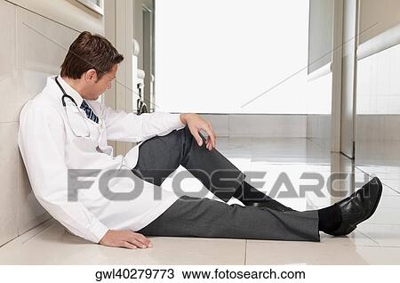 Doctor sitting on the floor looking depressed View Large Photo Image Stock Image - Doctor sitting on the floor looking depressed. Fotosearch