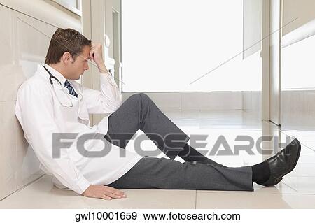 Doctor sitting on the floor looking depressed View Large Photo Image Stock Photo - Doctor sitting on the floor looking depressed. Fotosearch
