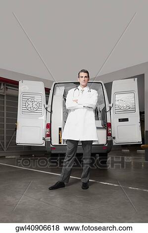 Doctor standing with an ambulance behind him View Large Photo Image Stock Photo - Doctor standing with an ambulance behind him. Fotosearch