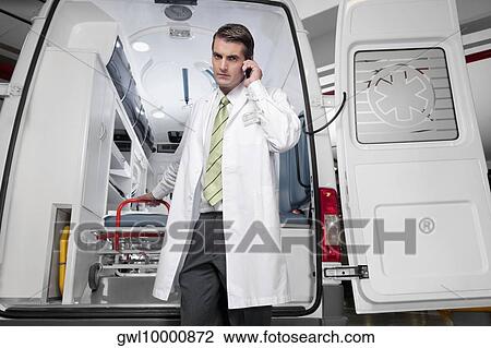 Doctor talking on a mobile phone in front of an ambulance View Large Photo Image Stock Image - Doctor talking on a mobile phone in front of an ambulance. Fotosearch