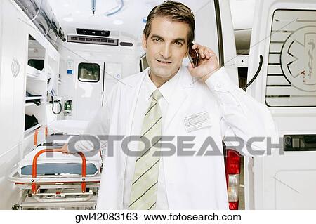 Doctor talking on a mobile phone in front of an ambulance View Large Photo Image Stock Image - Doctor talking on a mobile phone in front of an ambulance. Fotosearch