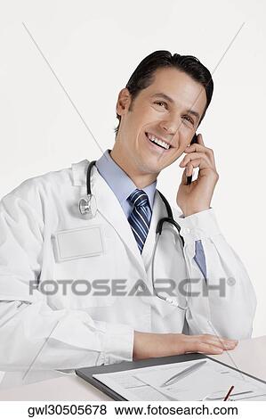 Doctor talking on a mobile phone View Large Photo Image Stock Photo - Doctor talking on a mobile phone. Fotosearch