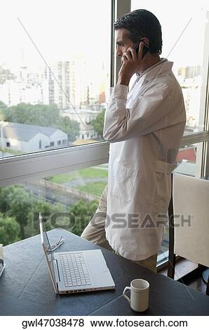 Doctor talking on a mobile phone View Large Photo Image Stock Photo - Doctor talking on a mobile phone. Fotosearch