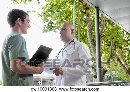 Doctor talking to a male nurse View Large Photo Image Stock Image - Doctor talking to a male nurse. Fotosearch